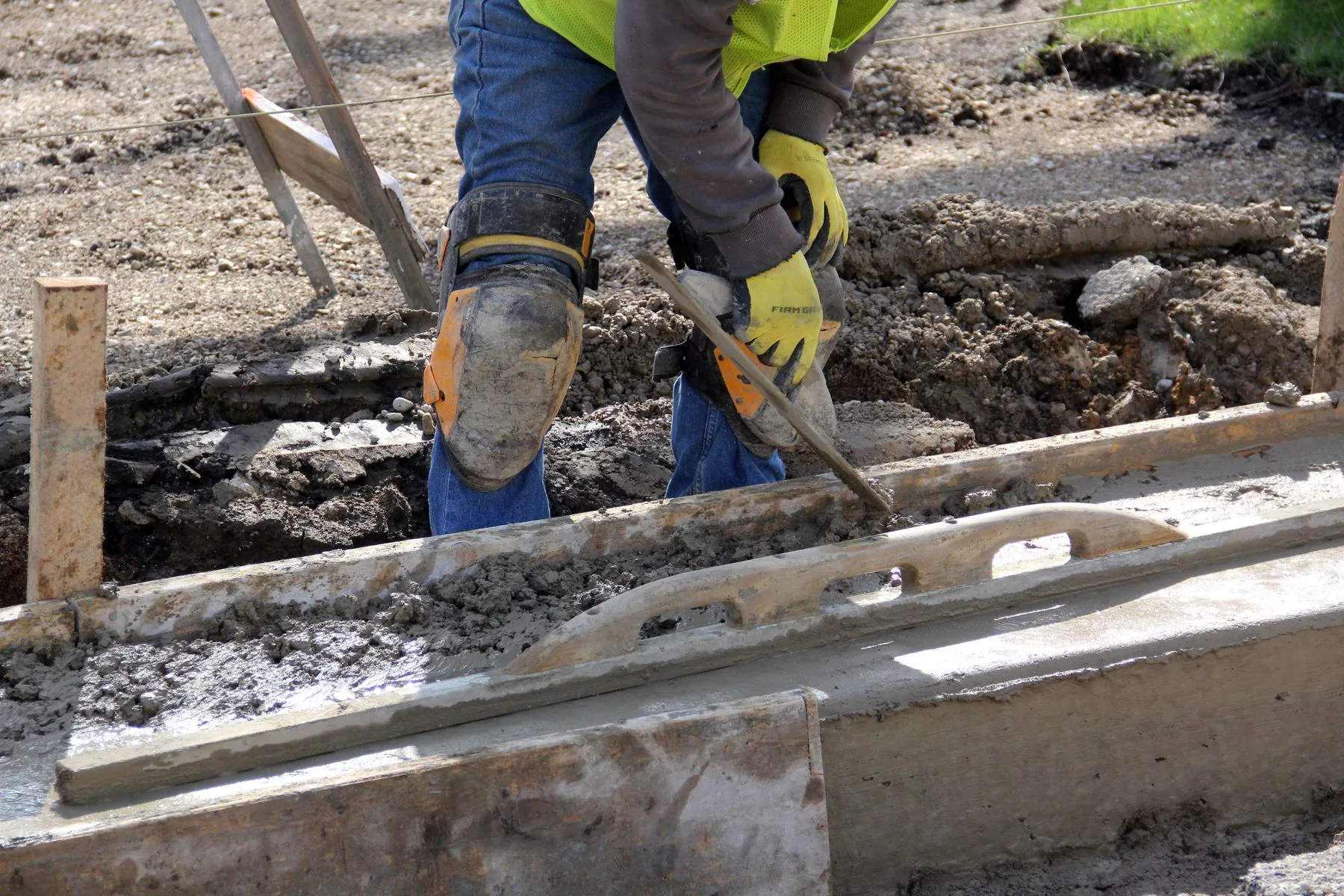 Concrete being finished by hand along timber formwork; illustrative stock photo