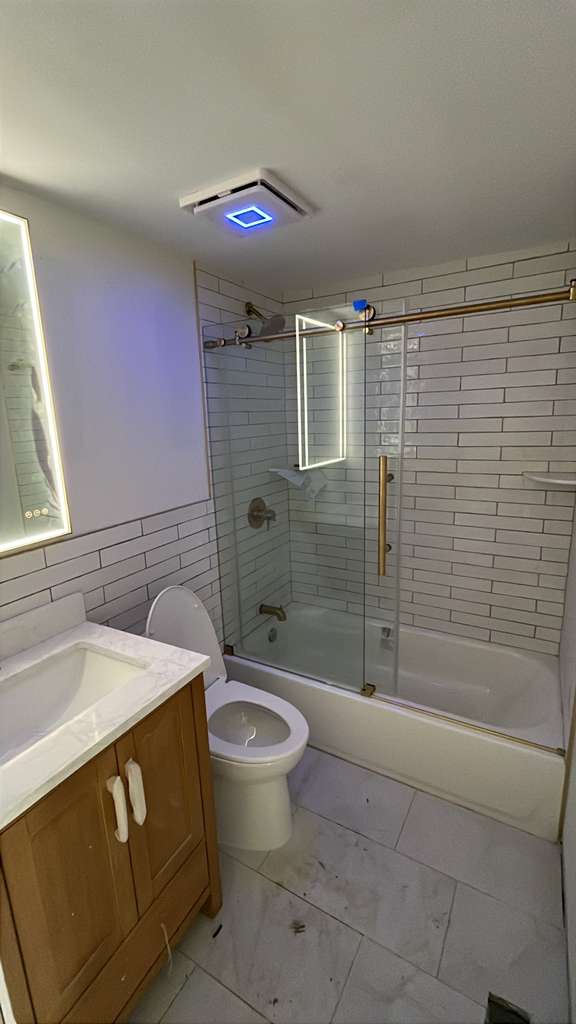 Finished bathroom with white tile, tub, and glass enclosure