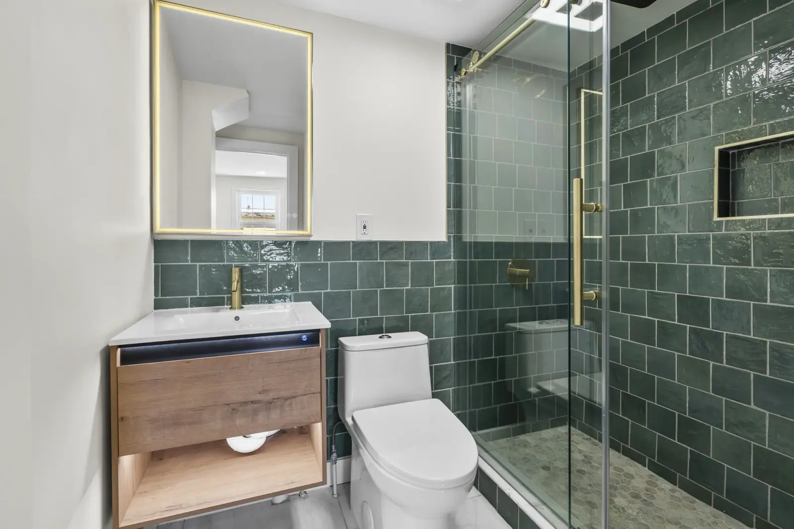 Finished bathroom with green tile shower and brass shower glass hardware