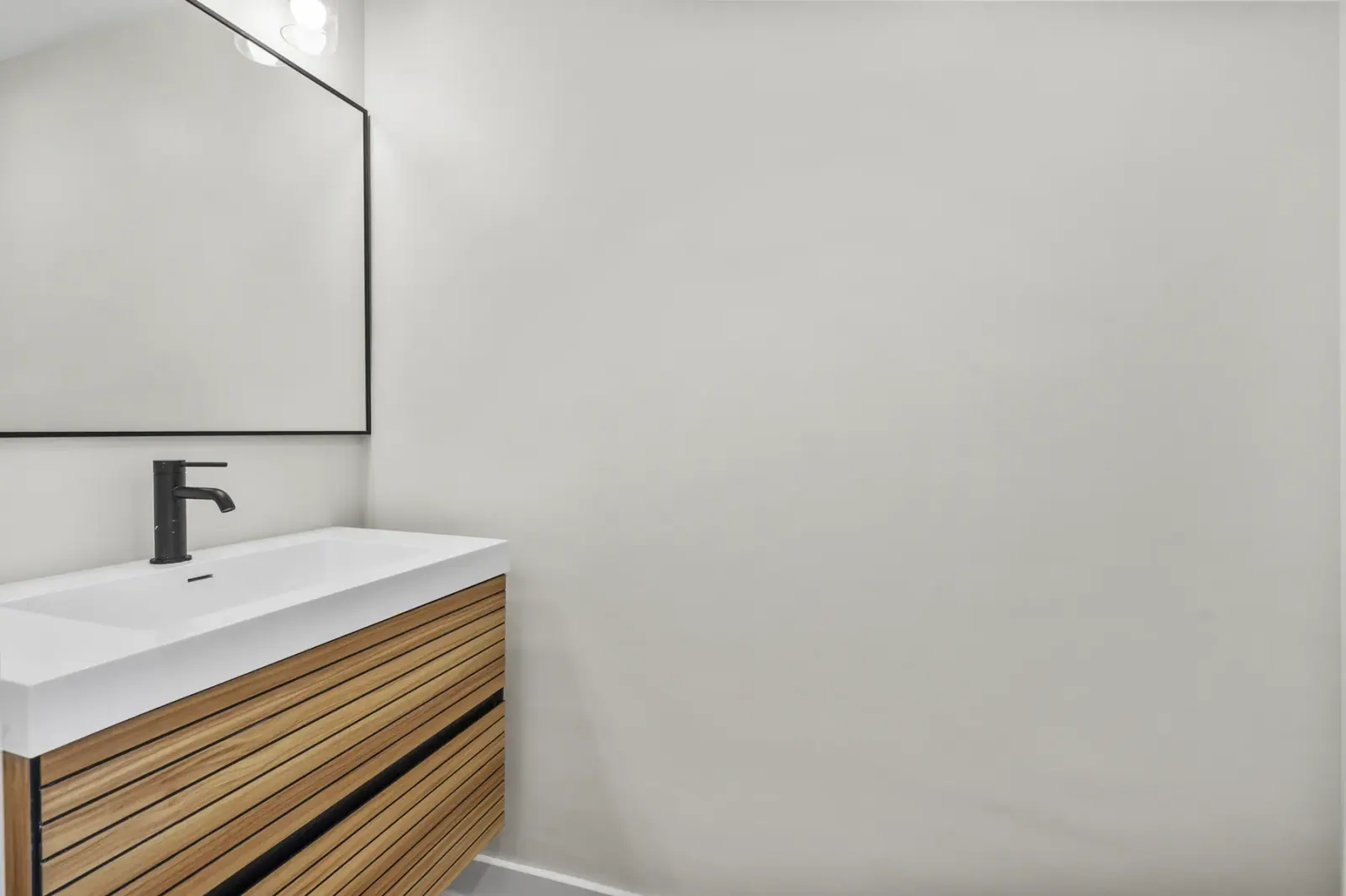 Finished bathroom vanity detail with wood vanity, black faucet, square sink, and mirror