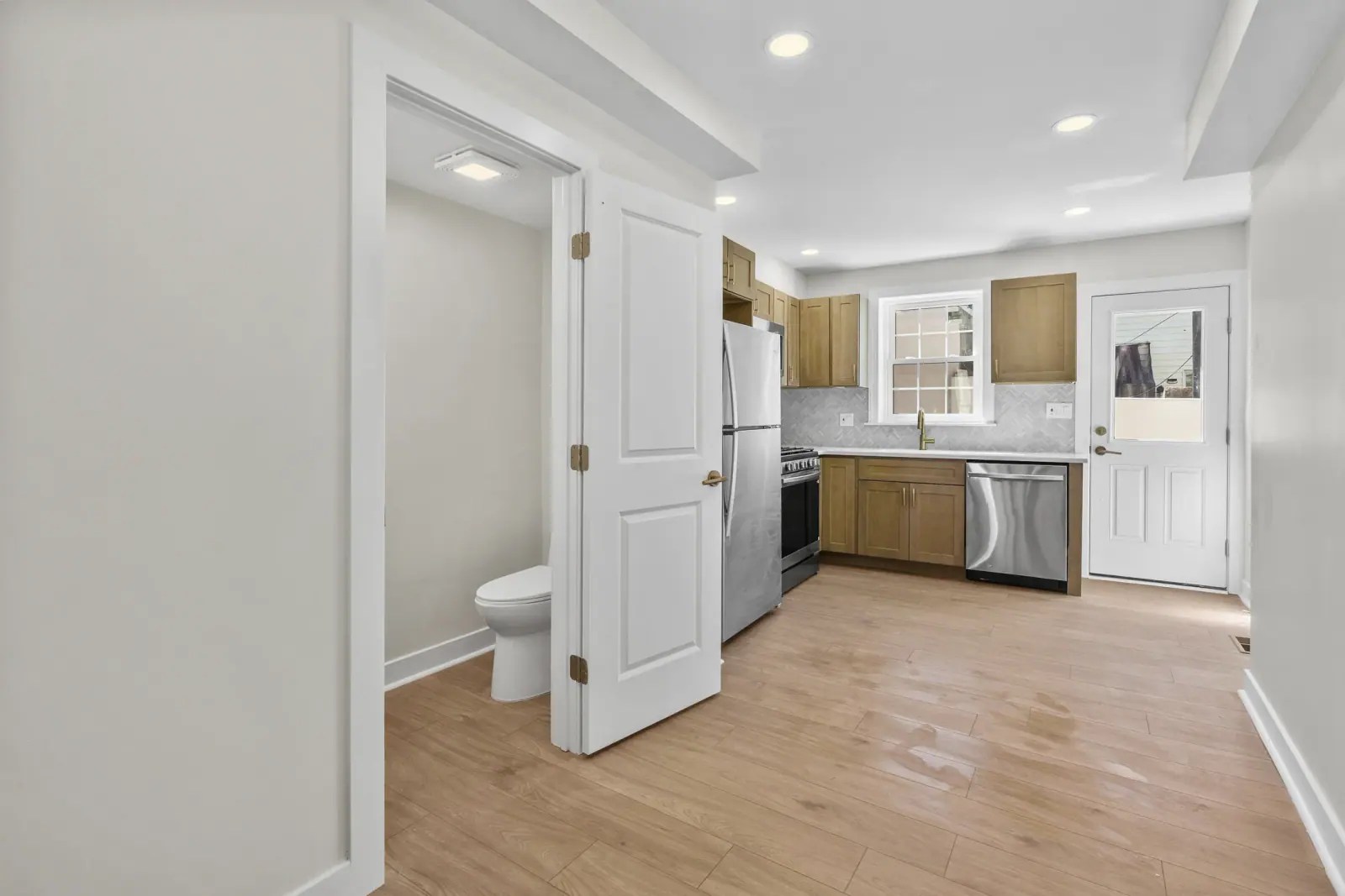 Finished kitchen and adjacent living space with new flooring, lighting, and connected room flow